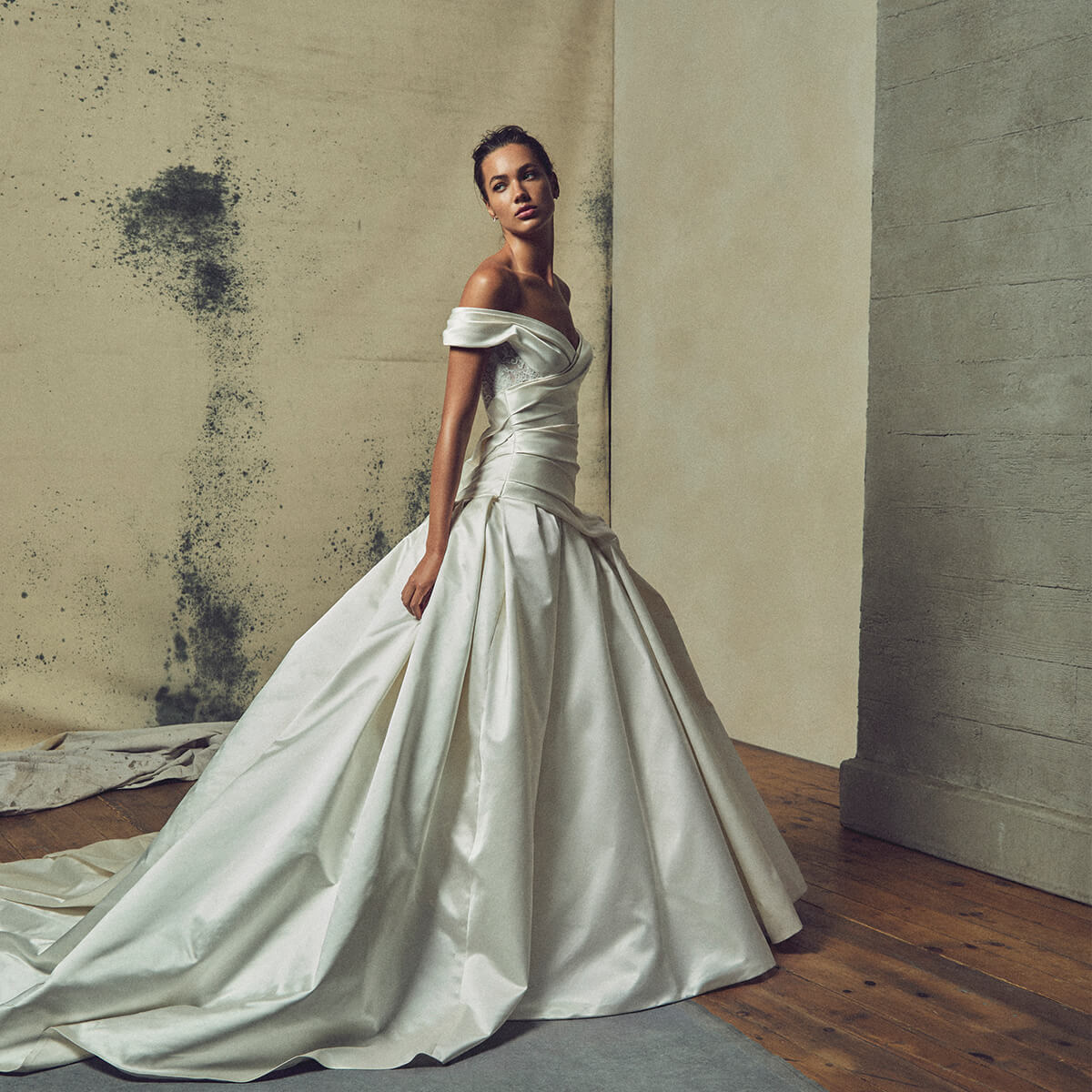 Monique Lhuillier Fall 2027 Bridal Endless Love Off-the-shoulder dropped waist ball gown with lace back corset in ivory silk duchesse satin and French re-embroidered lace.- lookbook.