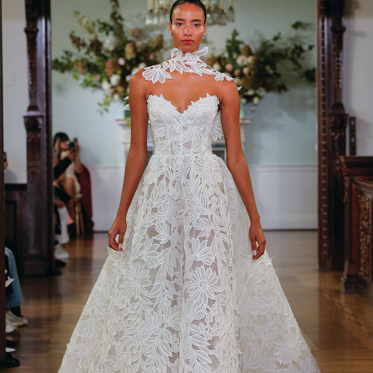 Monique Lhuillier Fall 2026 Bridal Ivory laser cut organza lace strapless Marisol ballgown with attached floral integral wrap - runway. 