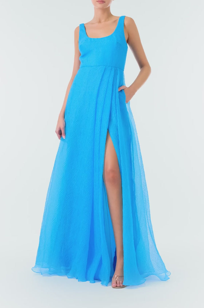 ML Monique Lhuillier 2024 scoop neck long dress with asymmetrical pleated front skirt and slit in Cyan Blue textured organza - video.