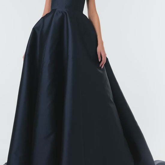 Monique Lhuillier Fall 2024 deep V-neck ball gown in navy mikado with full skirt and bow detail at shoulders - video.