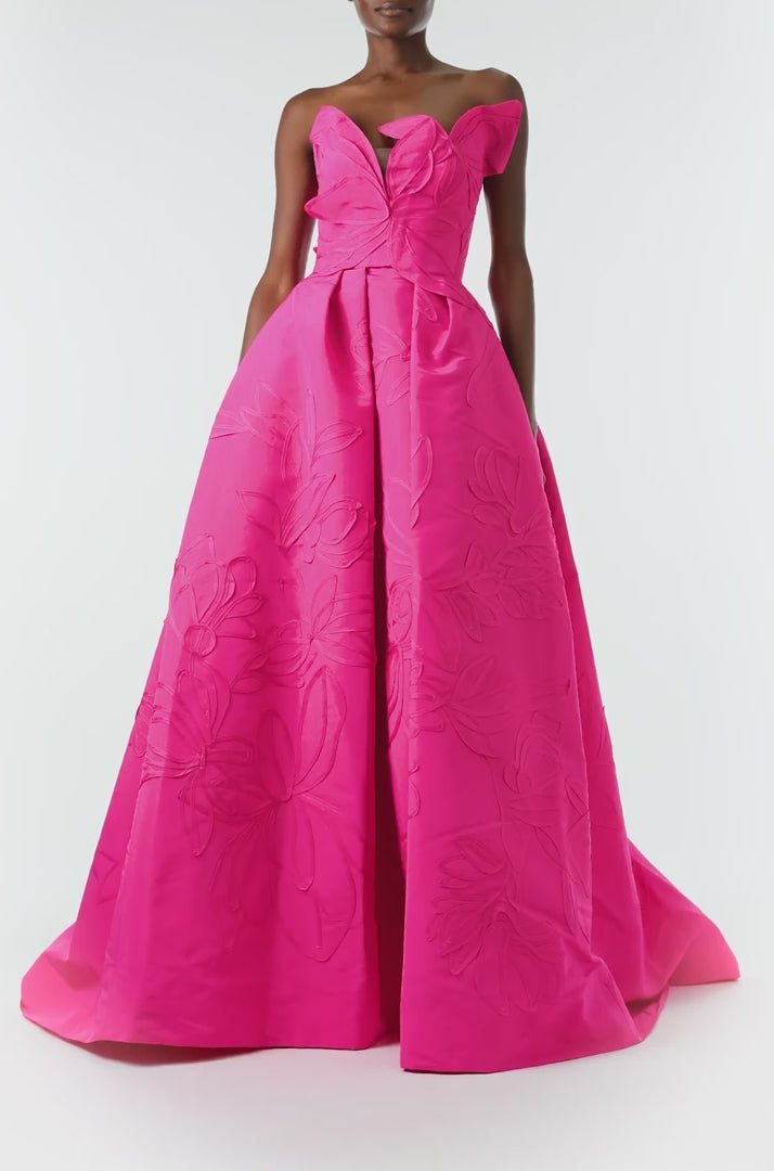 Monique Lhuillier Fall 2024 strapless, a-line ballgown in fuchsia floral embossed faille with draped asymmetrical bodice and full pleated skirt - video.