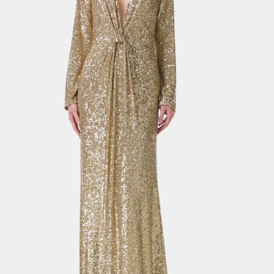 Monique Lhuillier long sleeve gown with deep v-neck and knot detail at waist in gold mini stretch sequin fabric.