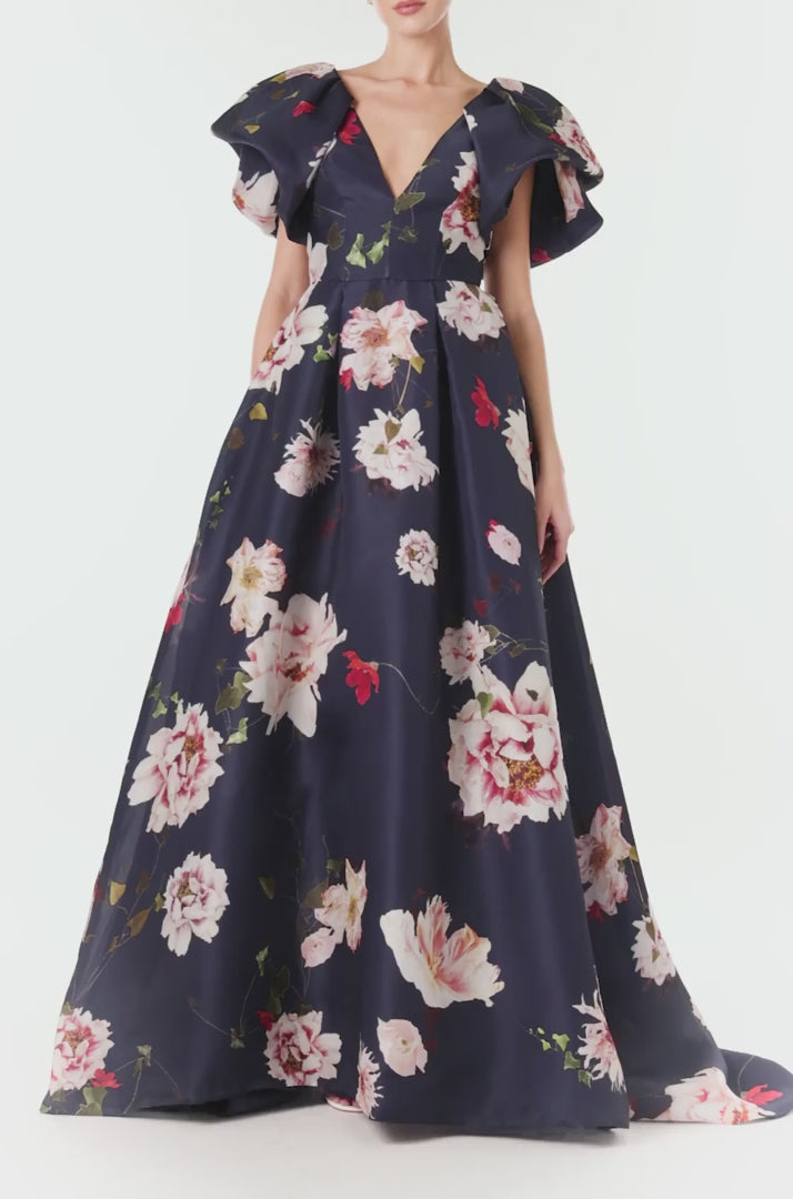 Monique Lhuillier navy floral gazar gown with deep v neckline, ruffle flutter sleeves and pockets.  