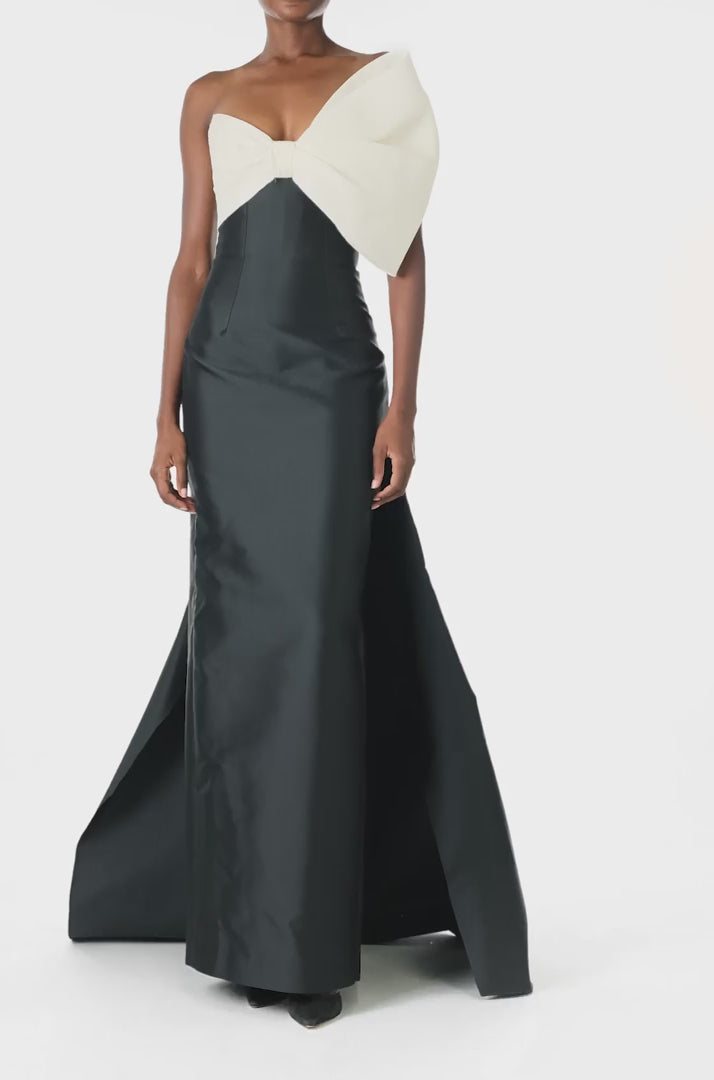 Monique Lhuillier Spring 2025 Strapless column gown with asymmetric draped bow neckline and pleated back train in Noir + Silk White Mikado - video.