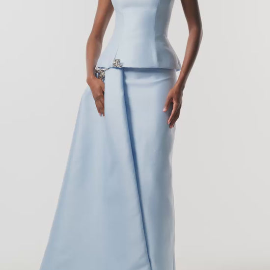 Monique Lhuillier Fall 2026 Pale Blue Mikado Piqué strapless dropped waist peplum gown with column skirt, side train and silver floral embellishment - video.