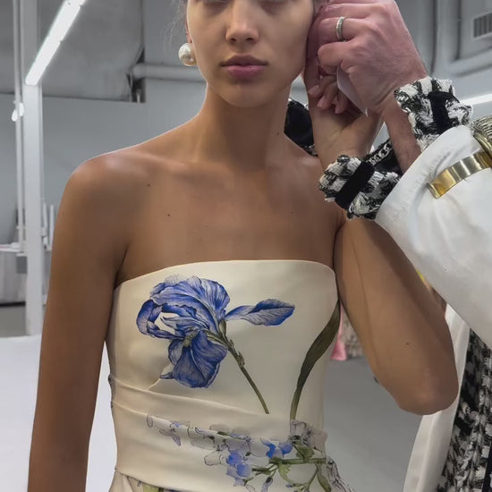 Monique Lhuillier Spring 2026 strapless, midi-length gown with draped peplum bodice in Ivory Iris Bouquet Printed Gazar - video.