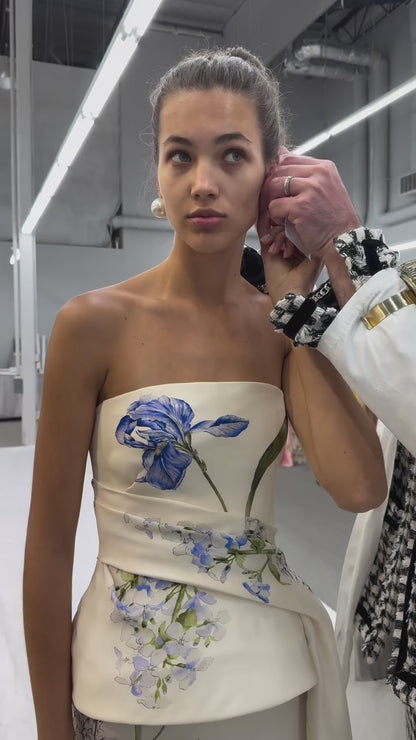 Monique Lhuillier Spring 2026 strapless, midi-length gown with draped peplum bodice in Ivory Iris Bouquet Printed Gazar - video.