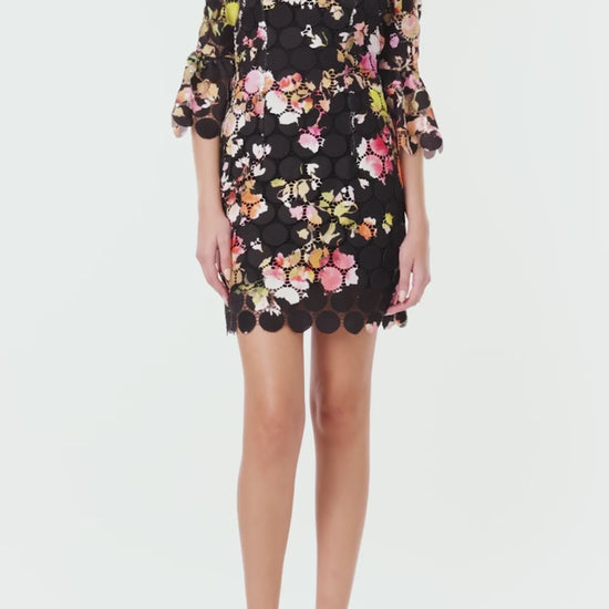 Monique Lhuillier Spring 2024 jewel neck mini dress in black/floral printed circle lace with bracelet length bell sleeves - video.