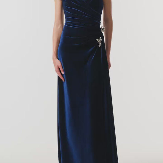 Monique Lhuillier Fall 2026 Navy off-the-shoulder stretch velour draped floor length gown with slit and silver floral embellishment - video.