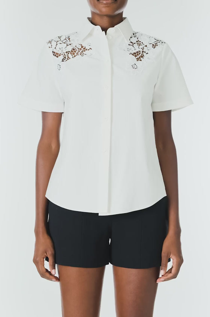 Monique Lhuillier Spring 2025 Short sleeve, button-down shirt with collar in white cotton poplin and lace applique details at shoulder - video.