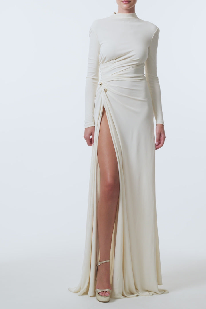 Monique Lhuillier Spring 2026 Ivory crepe jersey high neck long sleeved draped gown with slit and gold ball piercing - video.