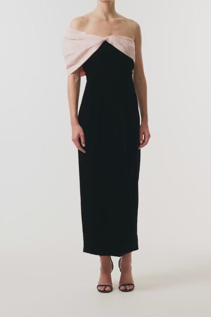 Monique Lhuillier Fall 2024 black velvet sheath dress with pale blush off the shoulder drapeda symmetric twist detail at neckline - video.