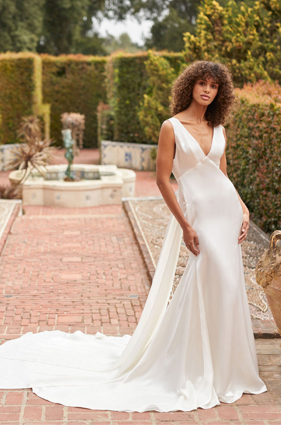 Model in white silk fitted v-neck gown with long train