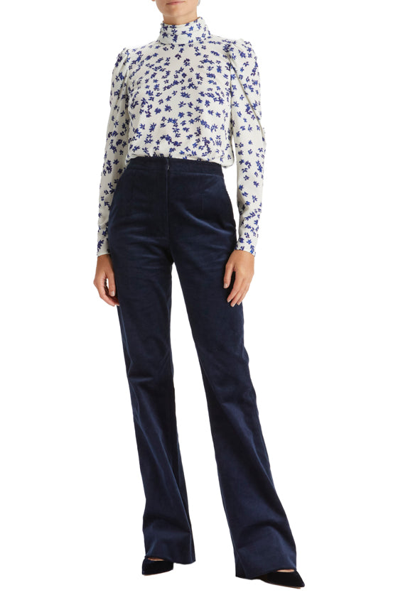 Woman in silk white and blue floral crepe blouse with high neck and long sleeves.