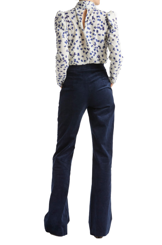Back view of woman in silk white and blue floral crepe blouse with high neck and long sleeves.